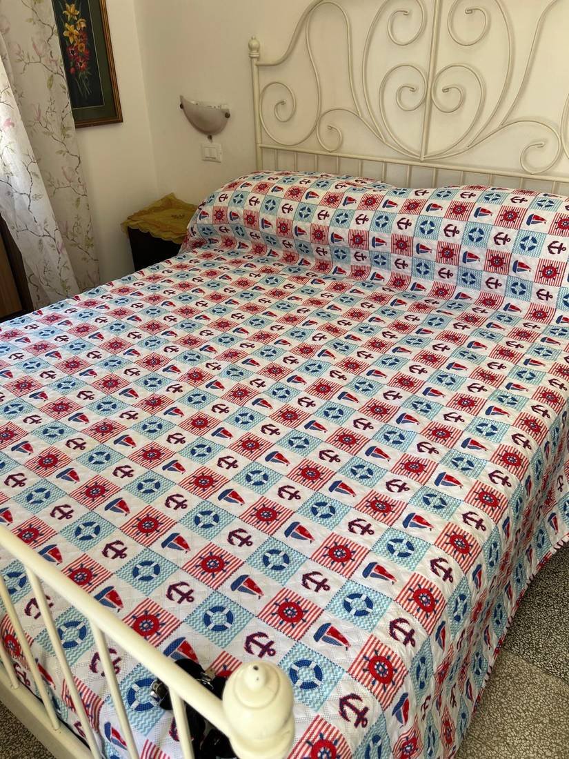 Camera con letto in ferro battuto e copriletto a tema marinaro